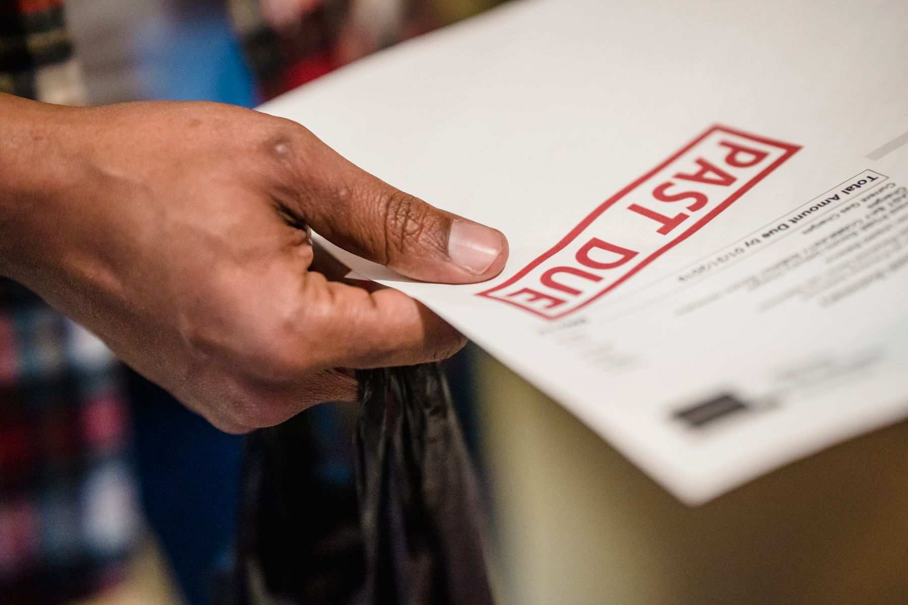 A hand holding a bill stamped past due